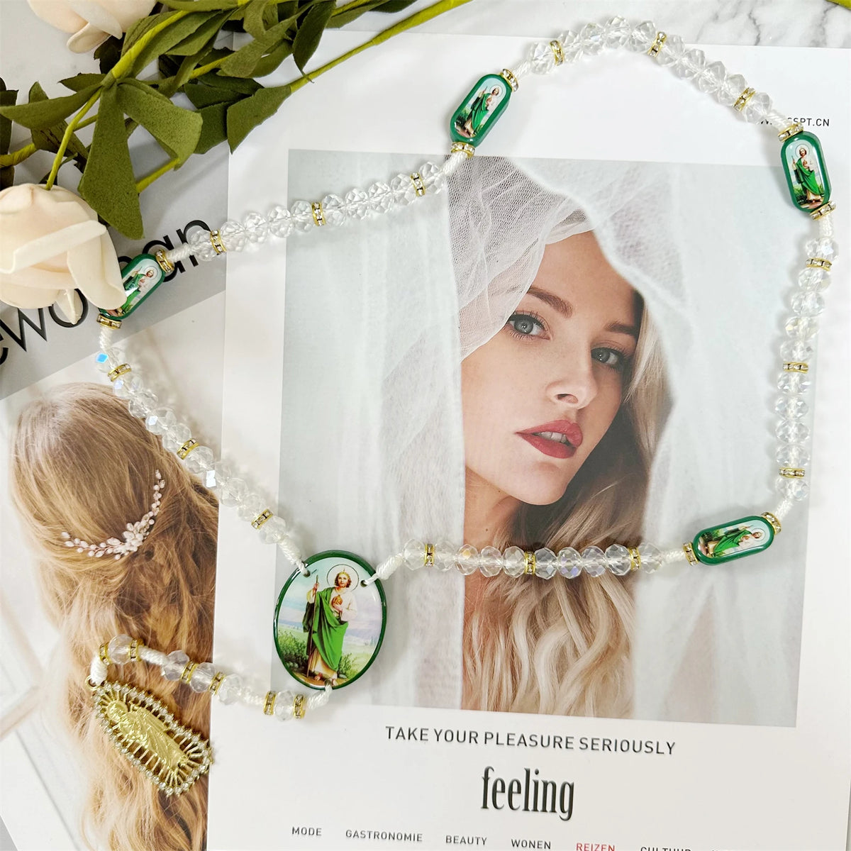 Green crystal rosary necklace with Saint Jude and Virgin Mary cross pendant displayed against a soft background.