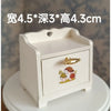 A white wooden miniature table with a lid featuring a decorative mushroom design.