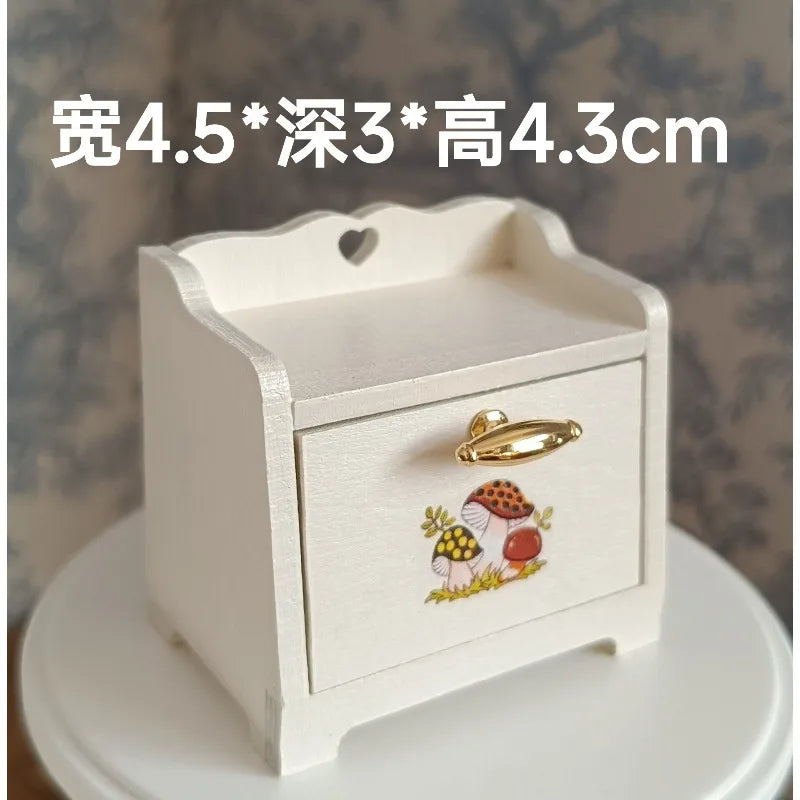 A white wooden miniature table with a lid featuring a decorative mushroom design.