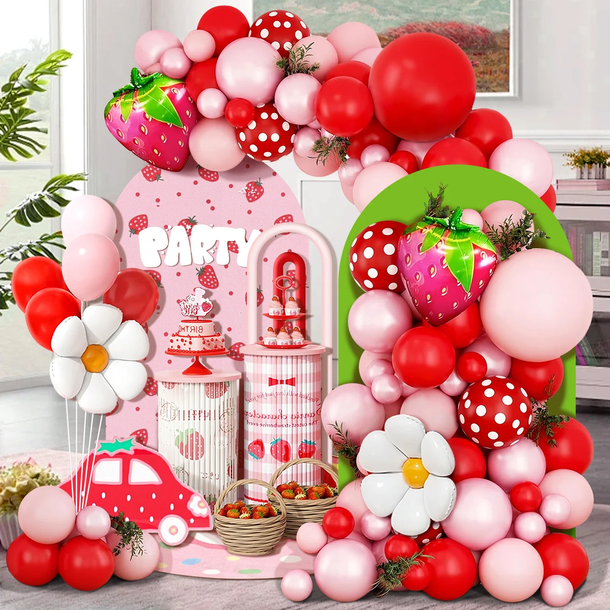 A colorful party decoration featuring a balloon arch wreath with pink, red, and white balloons and strawberry accents.