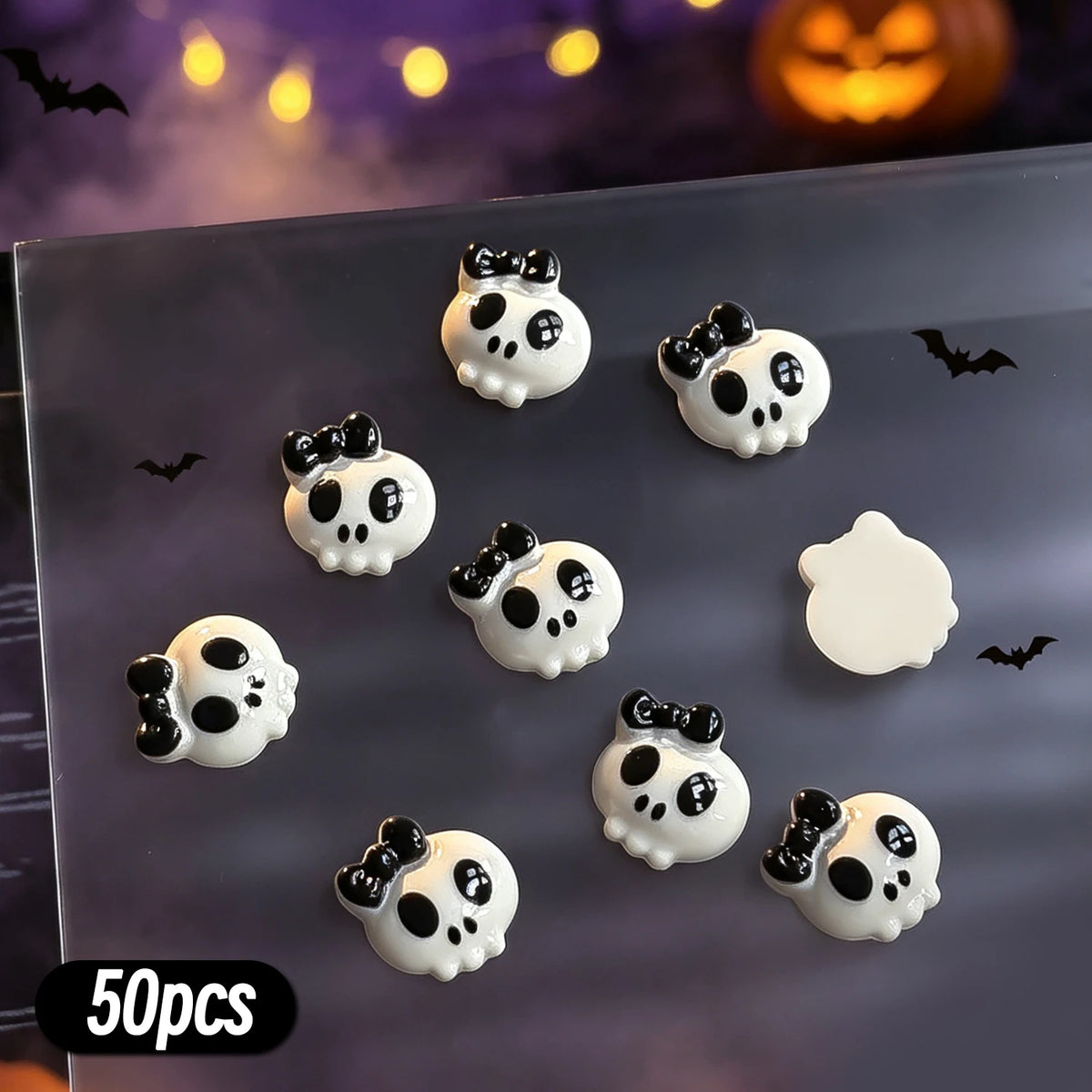 A variety pack of 50 black and white Halloween-themed resin nail charms featuring spooky faces and bats.