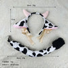 White and black cow print headband with pink ears, featuring ribbon bows and bells.