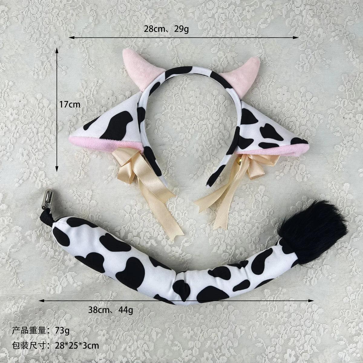 White and black cow print headband with pink ears, featuring ribbon bows and bells.