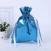 A blue festive drawstring gift bag with a silver ribbon and designs of Santa and a snowman.