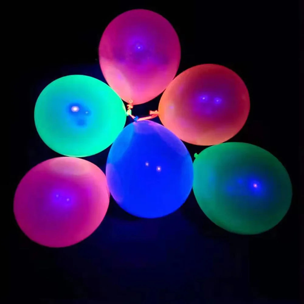A cluster of glowing latex balloons in shades of pink, purple, and green against a black background.