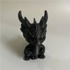 A black 3D printed mini dragon statue collectible with spiky horns sitting on a white surface.