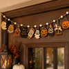 Vintage Halloween wooden hanging garland featuring retro pumpkin, ghost, and cat beads displayed on a dark brown wall.