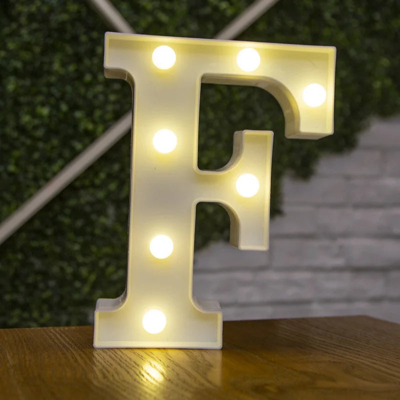 A glowing warm white LED alphabet letter light shaped like the letter F mounted on a wooden surface.