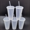 Five clear reusable tumblers with lids and straws standing upright against a dark background.