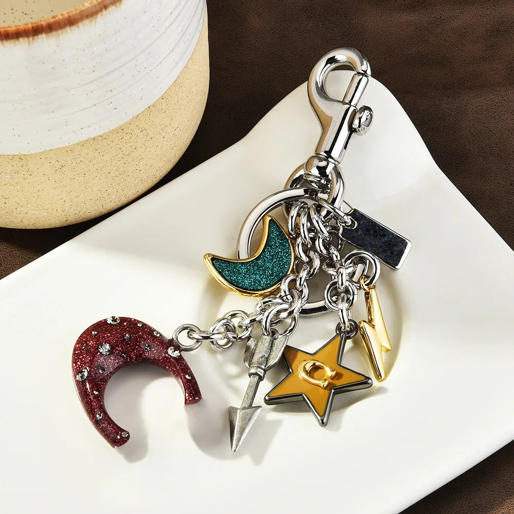 A silver zinc alloy keychain featuring a crescent moon charm and a gold star charm on a white plate.