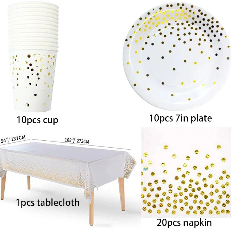 A set of gold polka dot disposable party tableware including a cup, plate, tablecloth, and napkin.