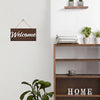 Rustic wooden welcome sign with the word Welcome mounted on a white wall above a wooden shelf.