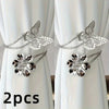 A set of two silver decorative flower butterfly curtain tiebacks displayed against a white curtain.