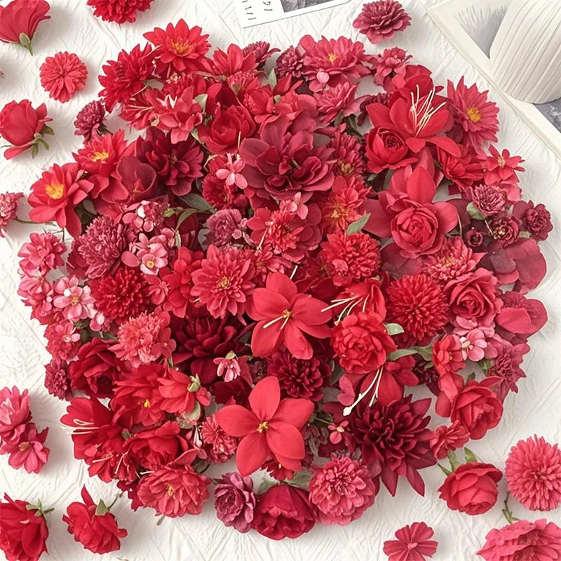 A dense arrangement of deep red and pink silk artificial flower heads for crafts and decor.
