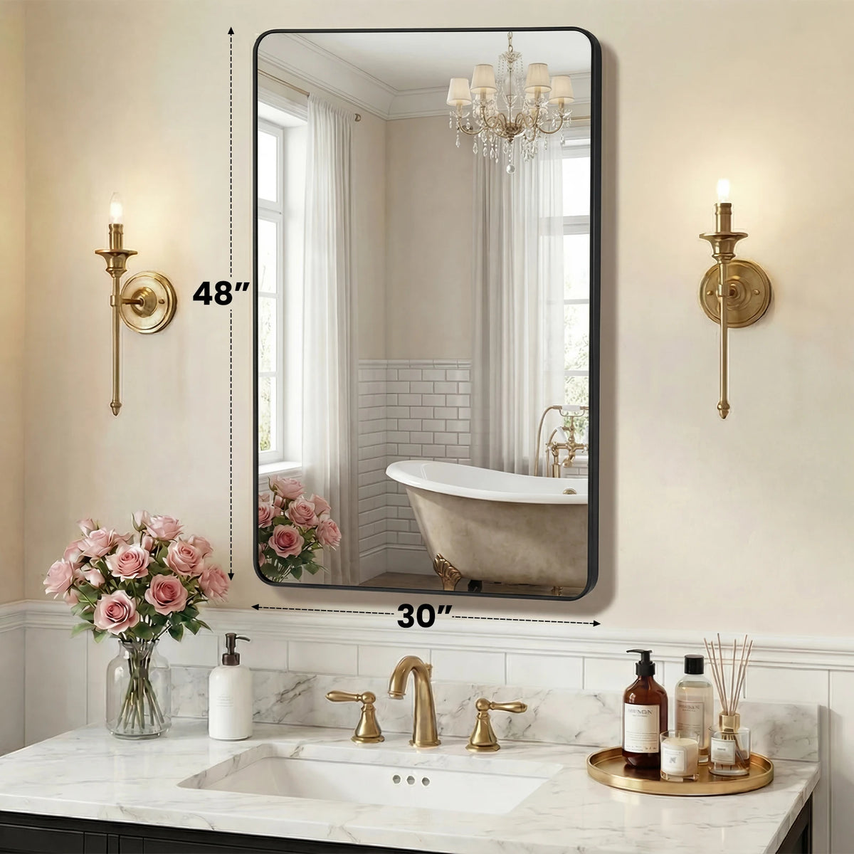 A modern wall mirror with a black metal frame reflecting a bathroom interior and a chandelier.