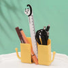 A yellow organizer holds a black cat-shaped ruler and various electronic accessories on a light green background.
