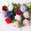A bouquet of realistic velvet artificial roses in shades of red, pink, purple, and white.