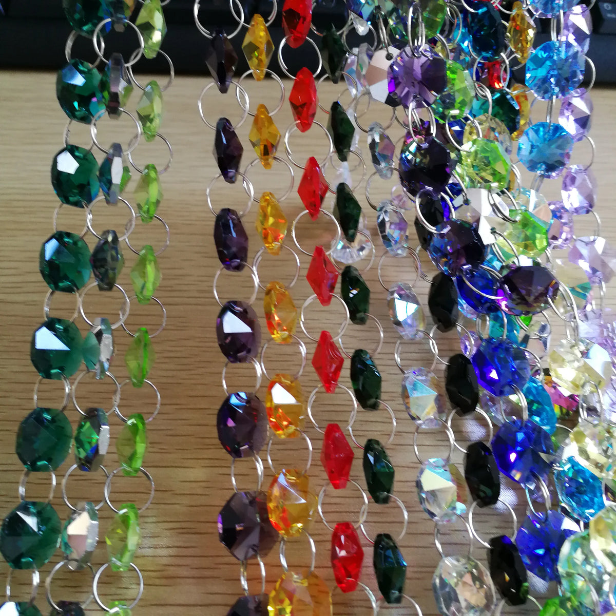 A close-up of crystal glass octagon bead curtain strands in various colors hanging vertically.