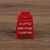 A red plastic sign with the text A LITTLE SIGN TO SAY I LOVE YOU engraved on it.