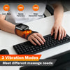 A hand is using a rechargeable heated wrist massager with vibration therapy on a laptop keyboard.