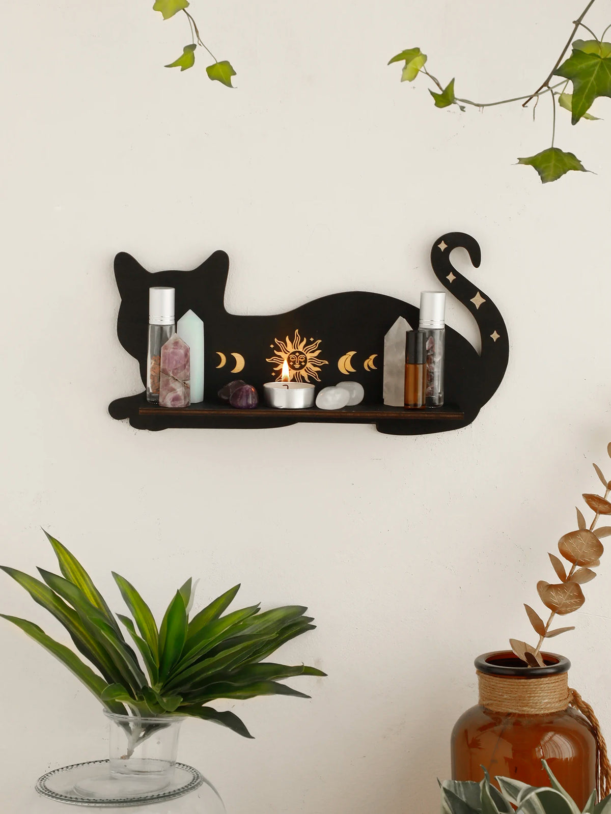 A black cat floating shelf displaying crystals, candles, and moon phase decor on a white wall.