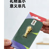 A FIFA 2026 World Cup trophy fridge magnet packaged in a cardboard holder.