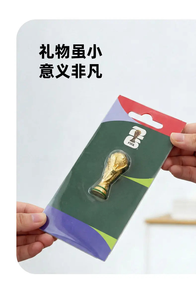 A FIFA 2026 World Cup trophy fridge magnet packaged in a cardboard holder.