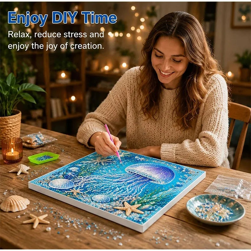 A woman is painting an ocean scene with diamonds on a canvas, surrounded by sea shells and glitter.