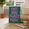 A teal canvas art poster featuring pink text that reads Play That Funky Music, displayed in a bright room.