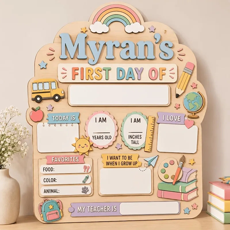 A wooden sign for a child's first day of school featuring illustrations like a school bus, rainbow, and various labels.
