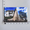 A photograph of the Reykjavik Cathedral with a modern glass structure in the background, printed on a fridge magnet.