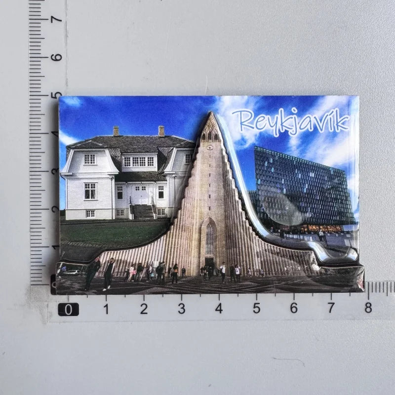 A photograph of the Reykjavik Cathedral with a modern glass structure in the background, printed on a fridge magnet.