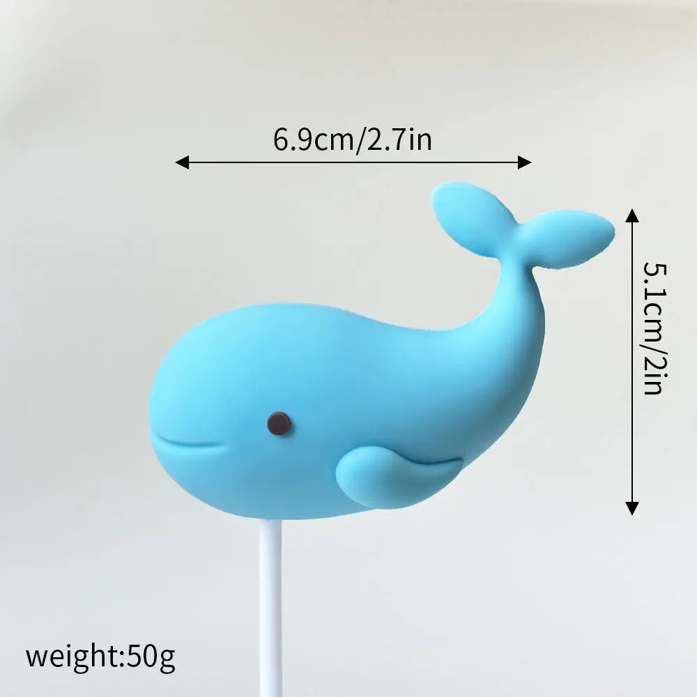 A light blue whale cake topper with a small brown nose, measuring 6.9cm long and 5.1cm high.