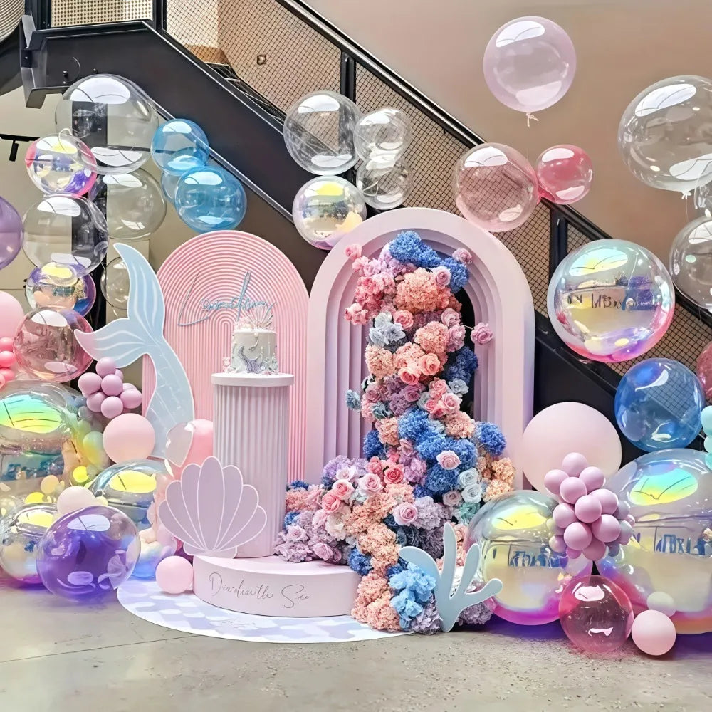 A display of metallic rainbow foil balloons in various shades and sizes arranged on a surface.