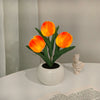 An orange tulip flower in a white ceramic pot, used as an LED night light.
