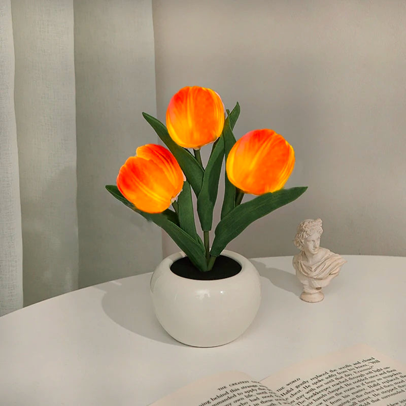 An orange tulip flower in a white ceramic pot, used as an LED night light.