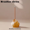 A natural citrine crystal is mounted on a wooden stick for use as an aromatherapy holder.