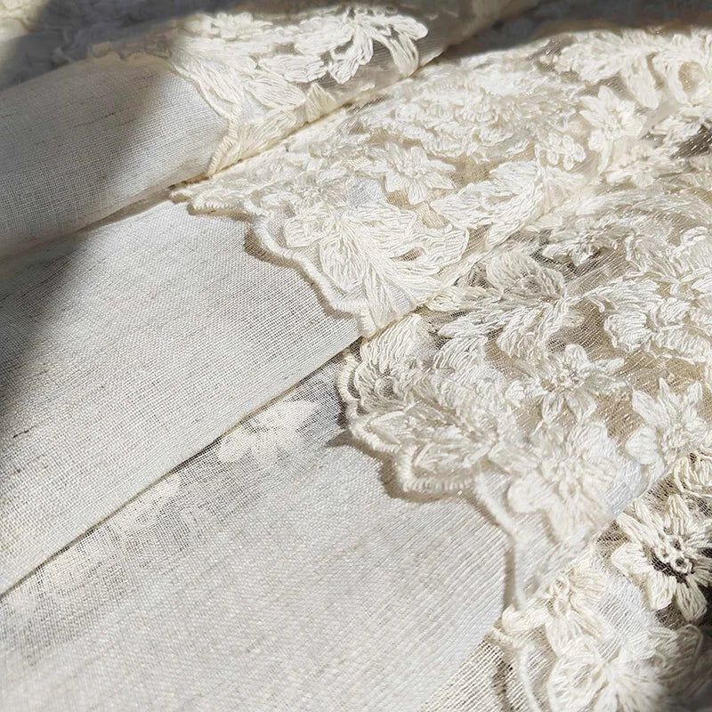 Beige sheer curtain fabric featuring delicate floral embroidery and lace trim.