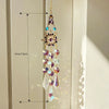 A hanging crystal rhinestone sun catcher featuring purple and blue stones, displayed against a light background.