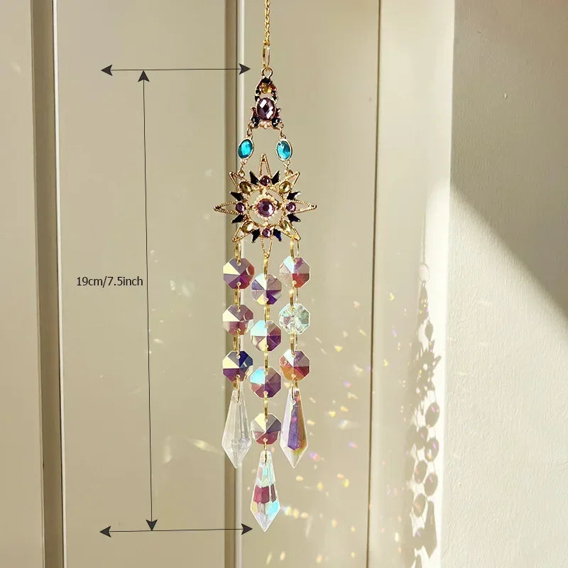 A hanging crystal rhinestone sun catcher featuring purple and blue stones, displayed against a light background.