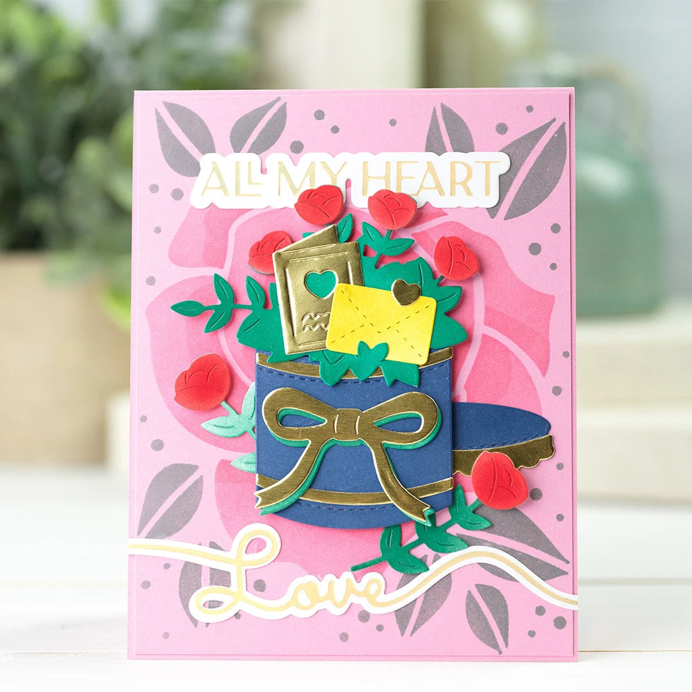 A pink card featuring the text All My Heart surrounded by green leaves and red floral elements.