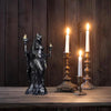 A dark resin statue of a fantasy goddess with mystical details stands on a wooden table against a dark wood background.
