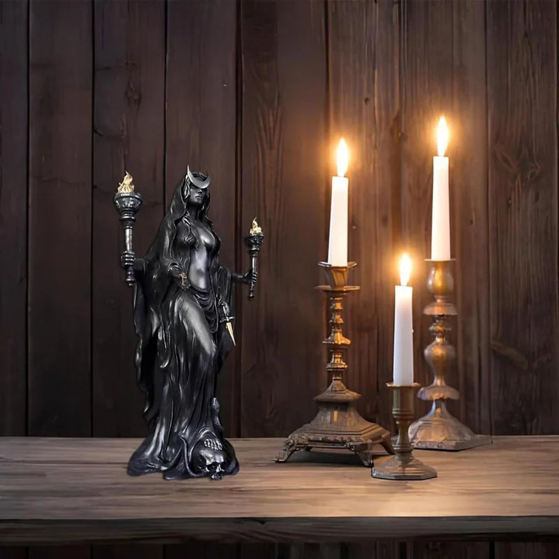 A dark resin statue of a fantasy goddess with mystical details stands on a wooden table against a dark wood background.