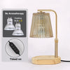 A brass adjustable electric candle warmer lamp with a clear glass shade and wooden base, shown next to instructions.