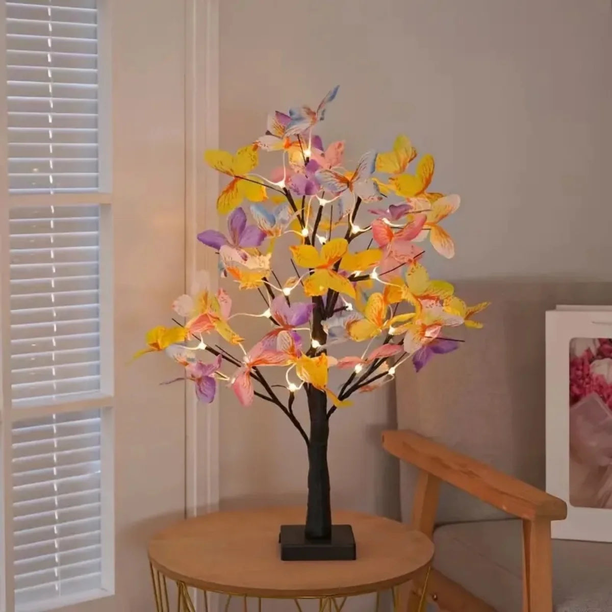 A decorative light display featuring colorful butterfly birch tree lights on a black stand.