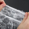 A hand is holding a clear reusable plastic food wrap cover with an elastic edge.