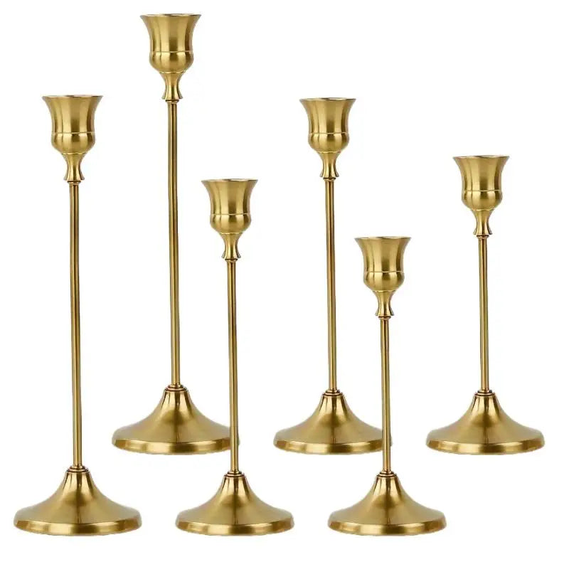 A set of three ornate vintage metal candle holders with brass finish.