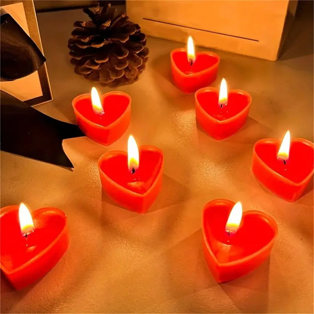 Un ensemble de bougies parfumées en forme de cœur rouges allumées sur une surface.
