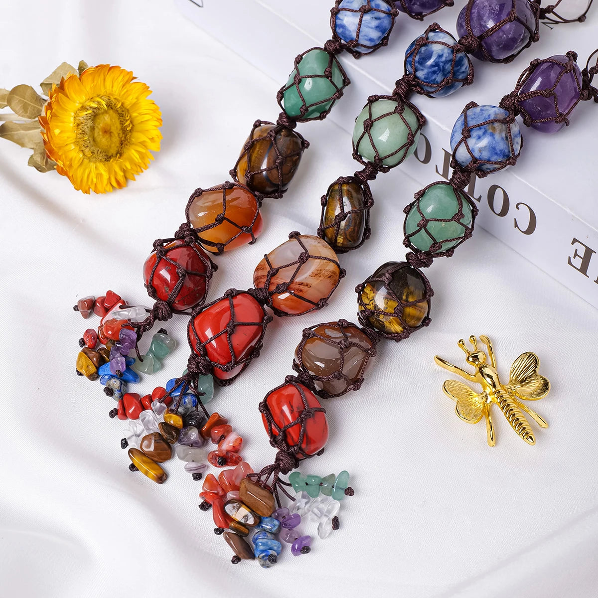 A collection of natural crystal rolling stone pendants in various colors and shapes laid out on a white surface.