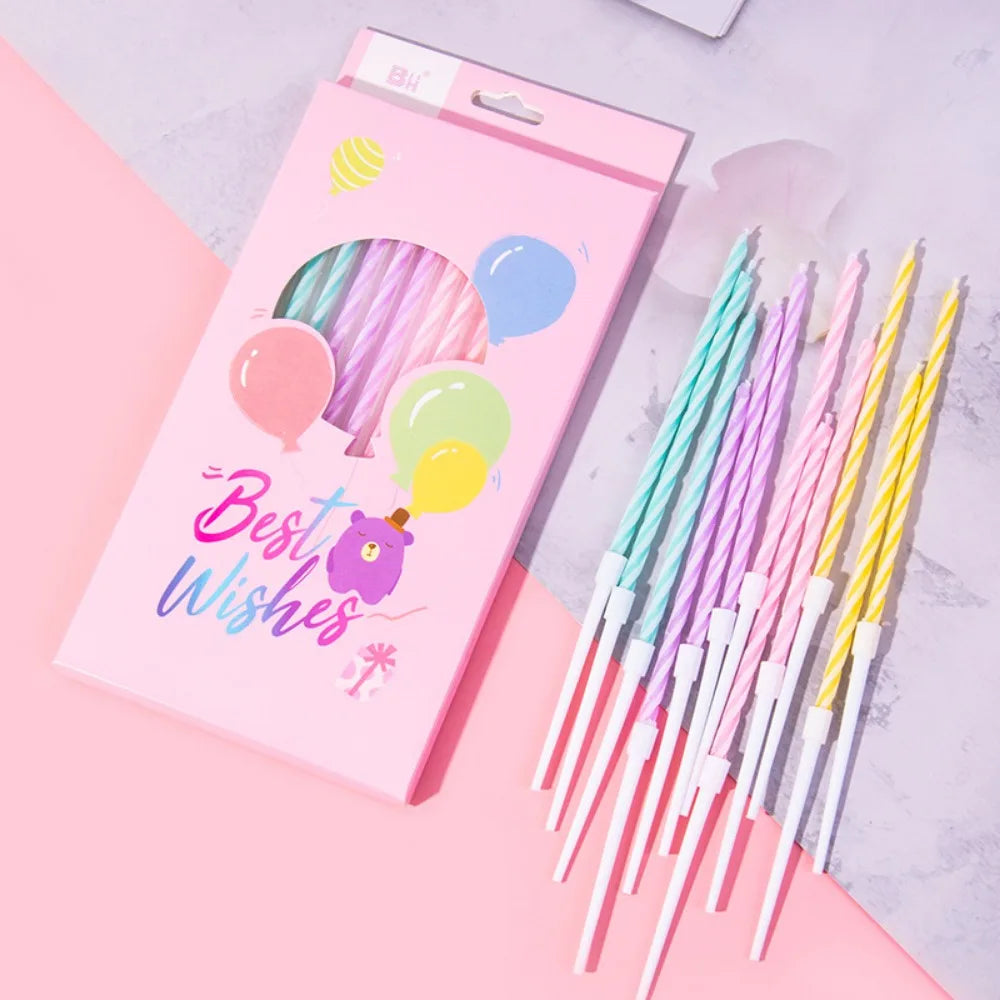 A pink card featuring colorful spiral candles and balloons, with a bundle of thin birthday candles beside it.